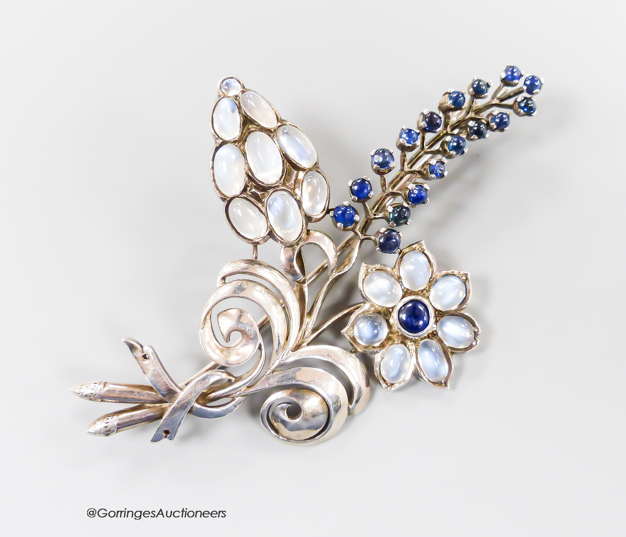A white metal, moonstone and cabochon blue quartz? cluster set floral spray brooch, 91mm, gross weight 28.6 grams.